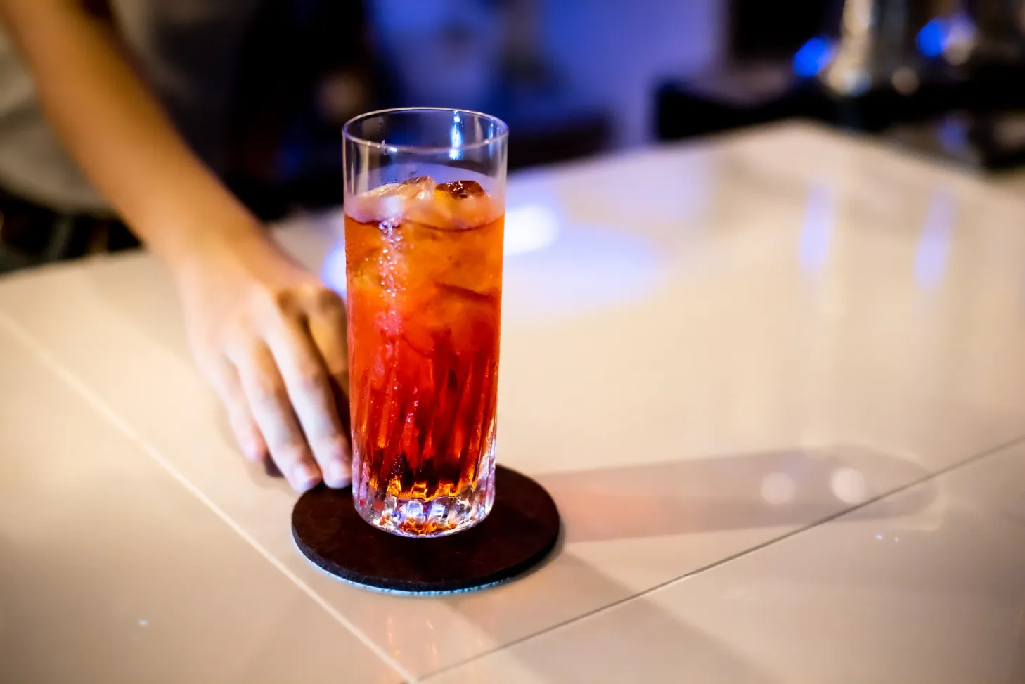 HACK.BARのカウンターでコースターに置かれた赤いカクテル